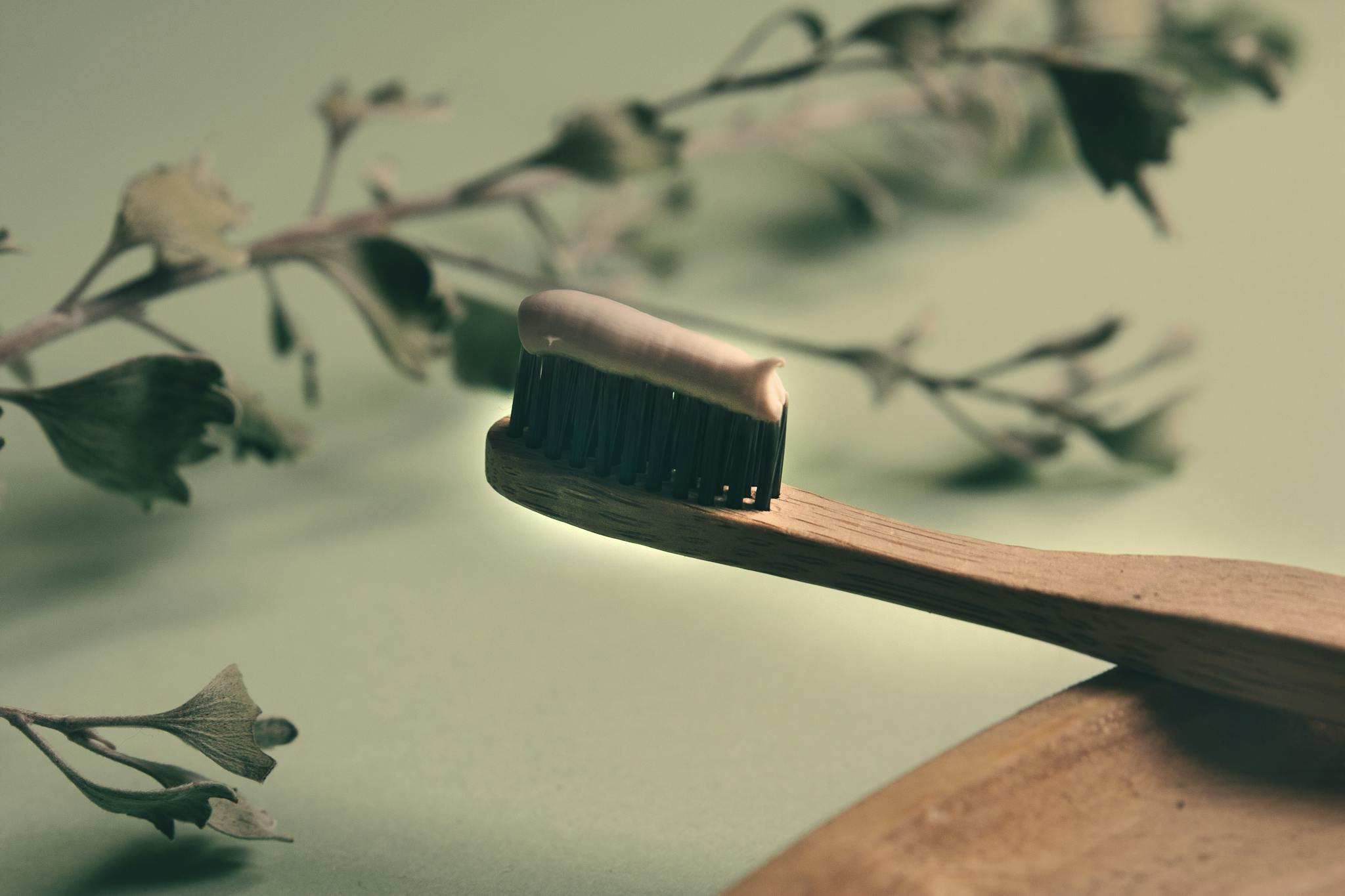 A close-up of a wooden toothbrush with toothpaste, highlighting eco-friendly dental care.