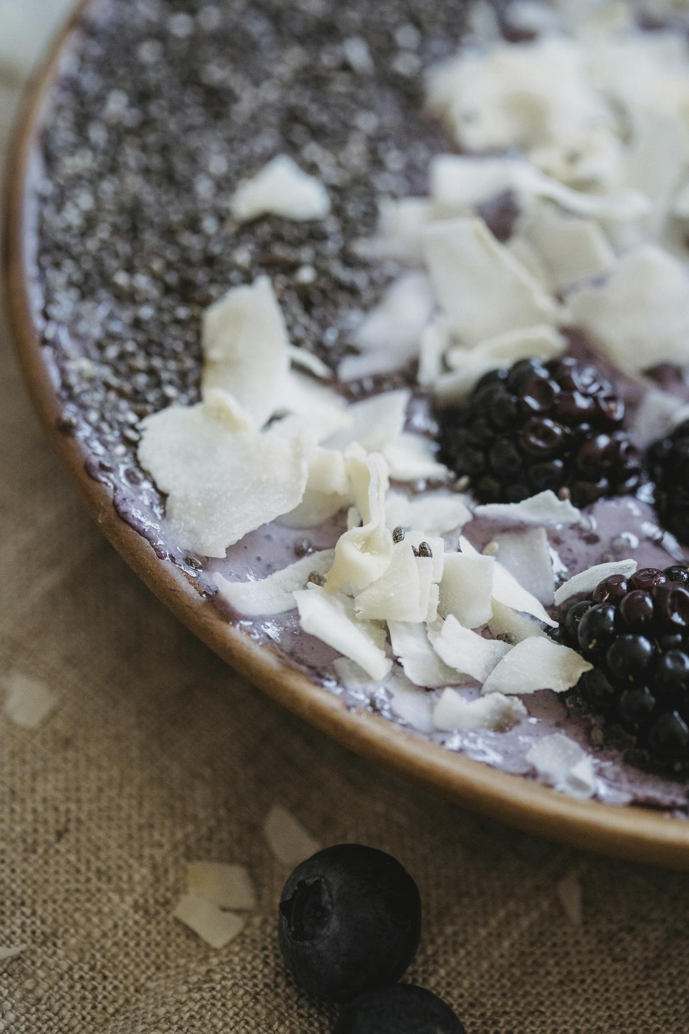 Close-up of a breakfast bowl with blackberries, blueberries, chia, and coconut shavings.