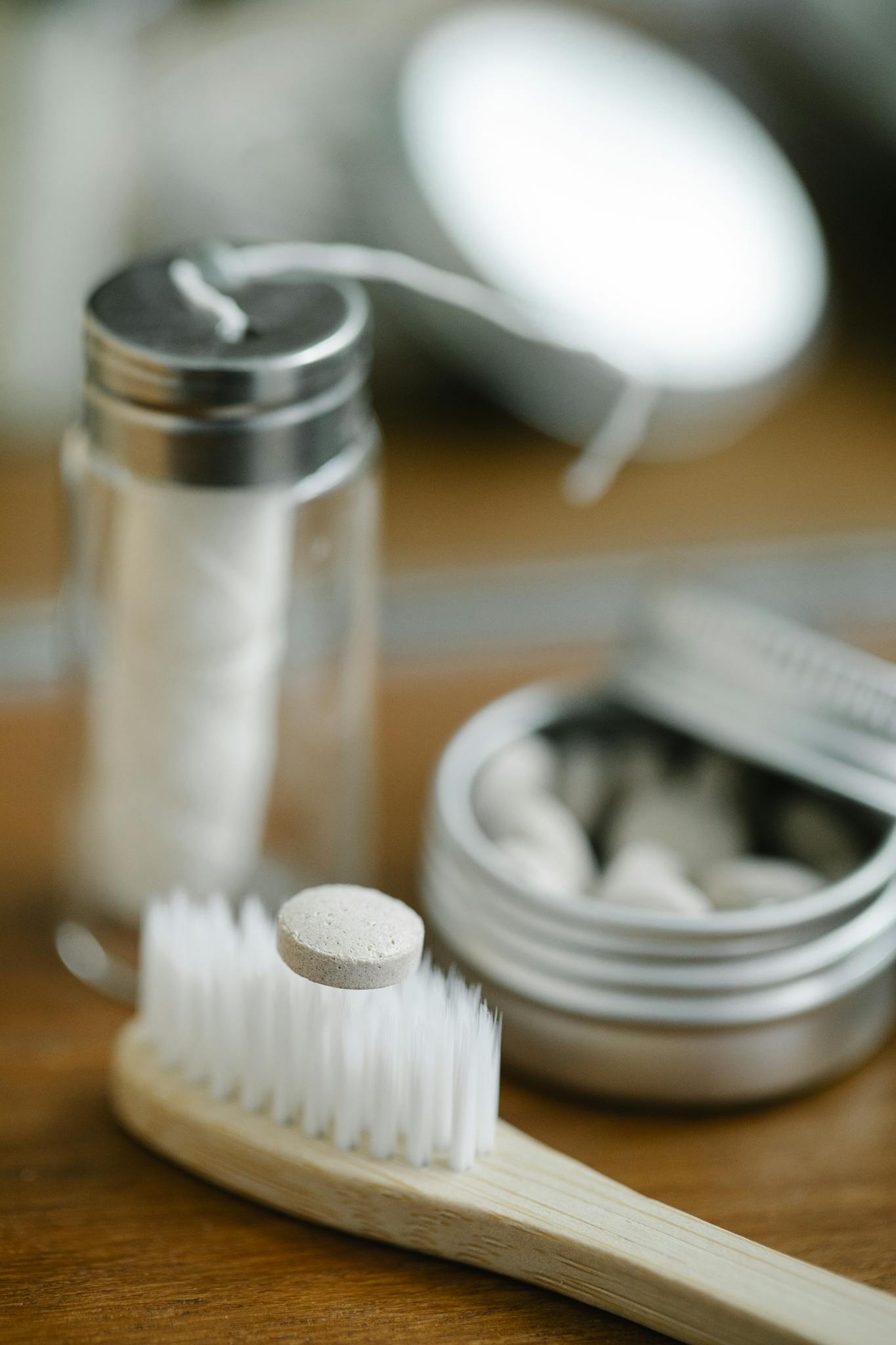Sustainable wooden toothbrush with dental floss and tablets in a modern bathroom setting.