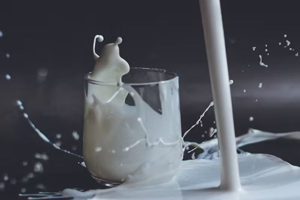 Milk being poured into a glass with a black background